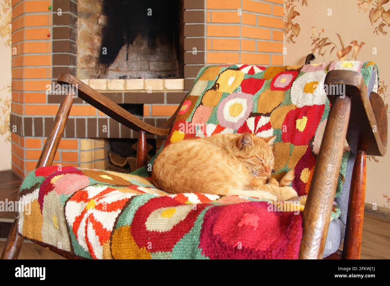 Il gatto dorme su una sedia a dondolo sullo sfondo del camino Foto Stock