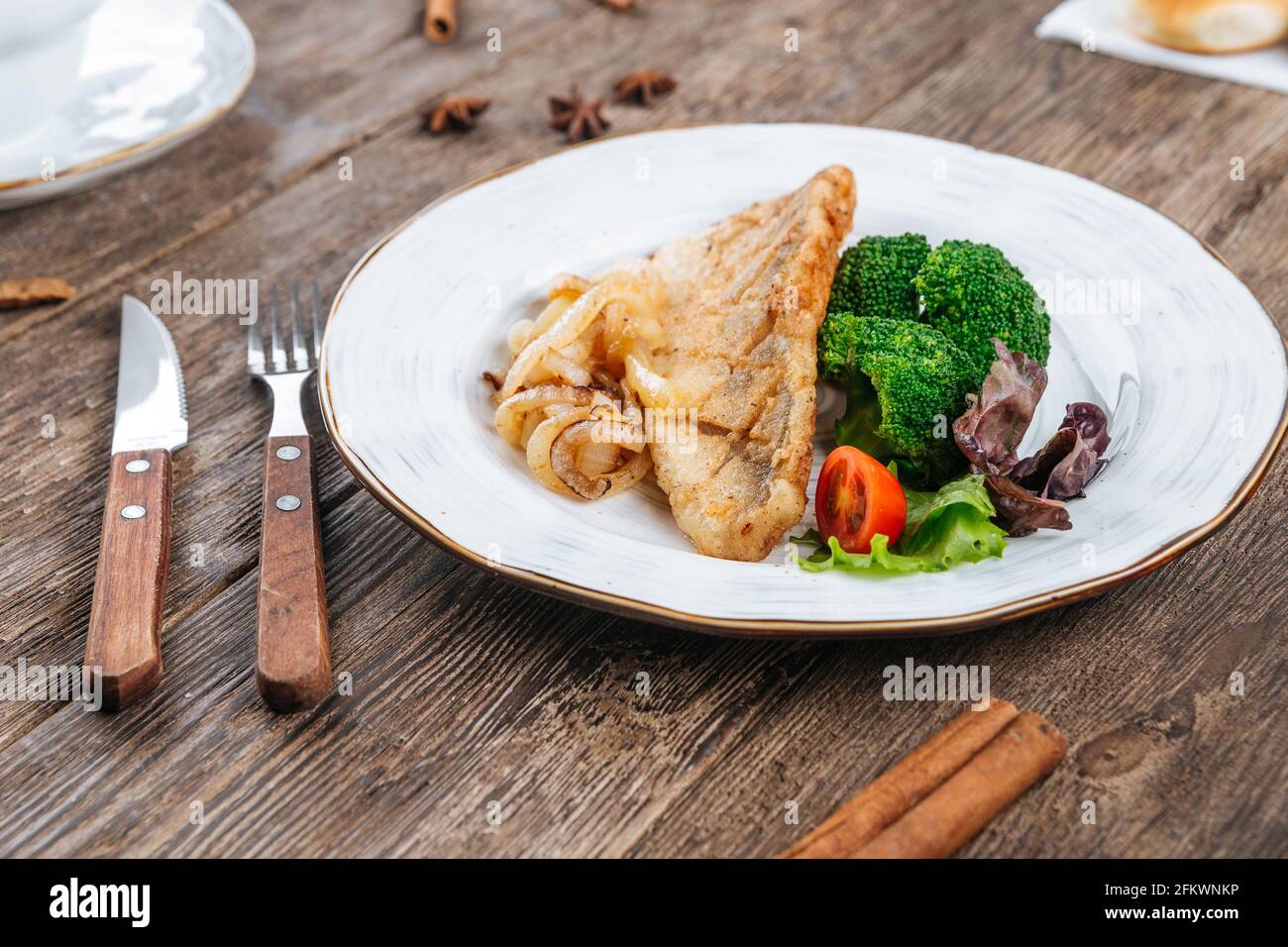 Filetto di pesce fritto con verdure fresche su un tavolo Foto Stock