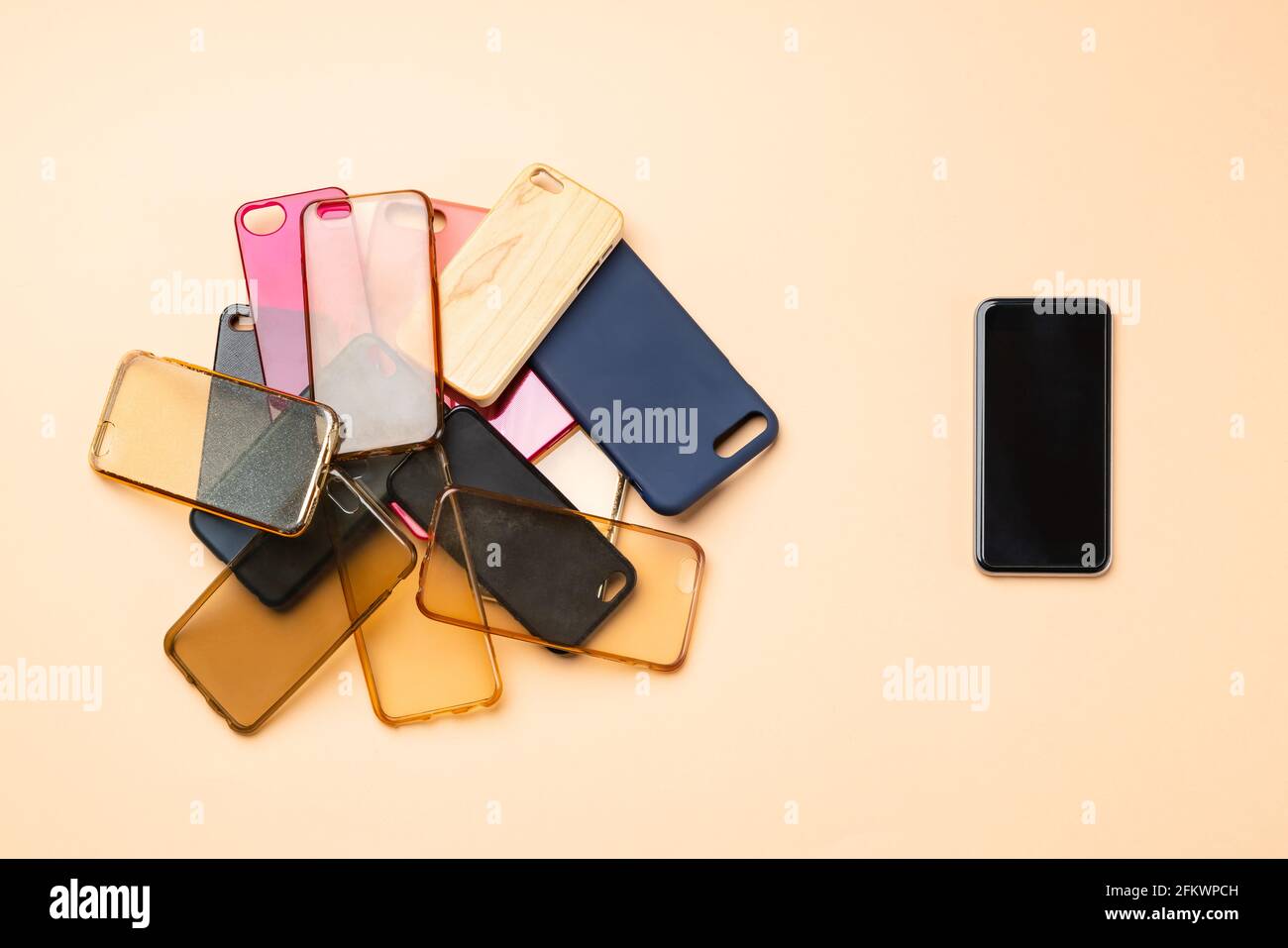 Possibilità di scelta tra cover posteriori in plastica multicolore per telefoni cellulari sfondo neutro con uno smartphone sul lato Foto Stock
