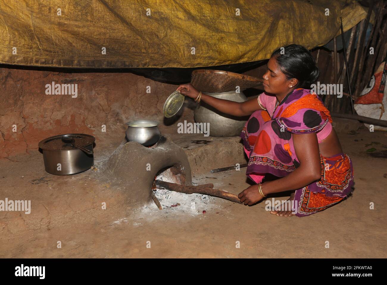 Donna che cucina cibo utilizzando tradizionale fango focolare. TRIBÙ DESIA KONDHA. Goipeta Village, Odisha, India Foto Stock
