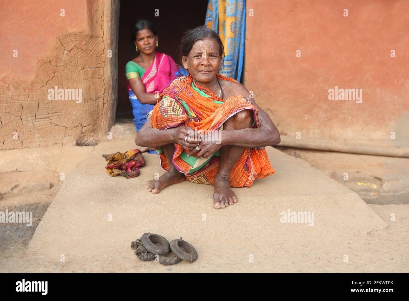 Anziana, TRIBÙ DESIA KONDHA. Seduto all'esterno che mostra i tradizionali bracciali di ferro. Odisha, India Foto Stock