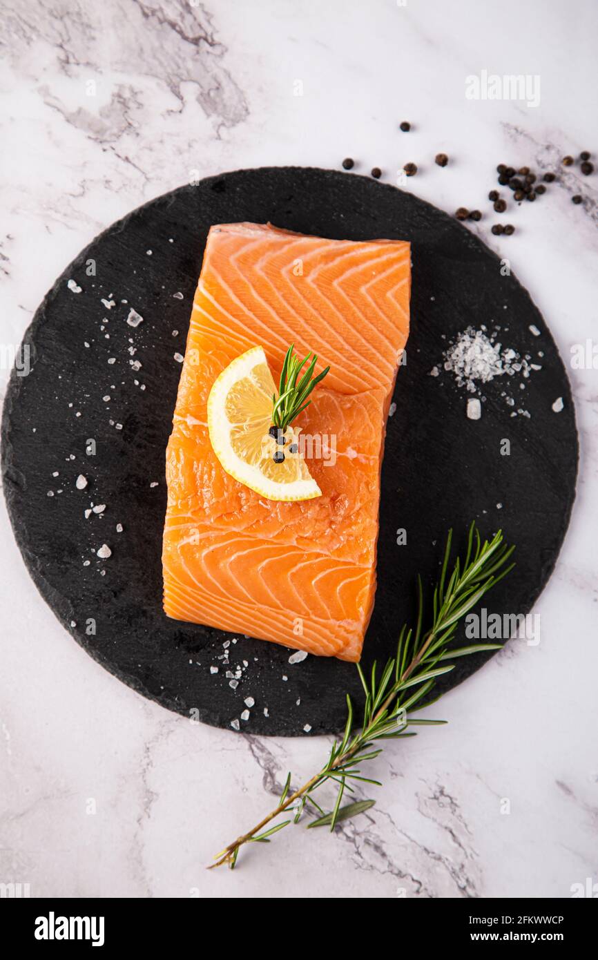 Vista aerea del salmone crudo su ardesia con limone e rosmarino sul tavolo Foto Stock