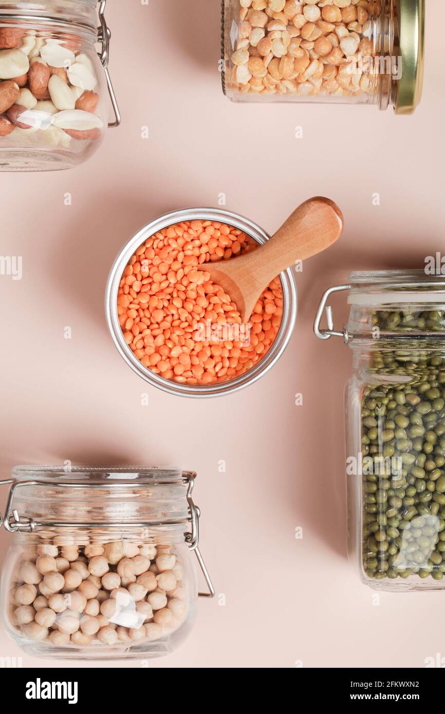 Fonte proteica vegana. Piselli, ceci, lenticchie, mung, arachidi in vasi di vetro su sfondo bianco e beige. Cibo vegetariano sano. Copia spazio Foto Stock