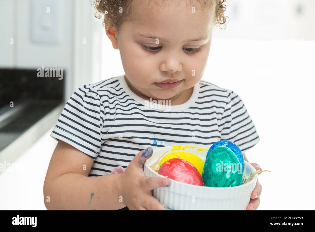 Il bambino è molto attento a non far cadere un cestino con le uova di Pasqua. Foto Stock