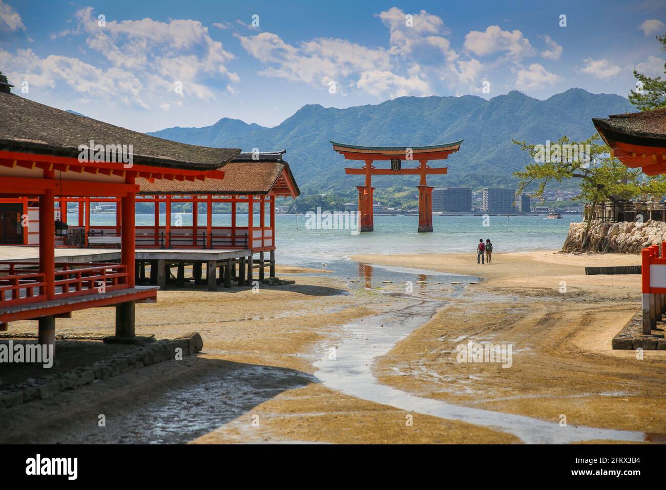 Itsukushima Floating Torii Gate. Passeggiata romantica sulla spiaggia per una coppia all'antico Santuario giapponese Shinto sull'isola di Miyajima, Hiroshima, Giappone. Foto Stock