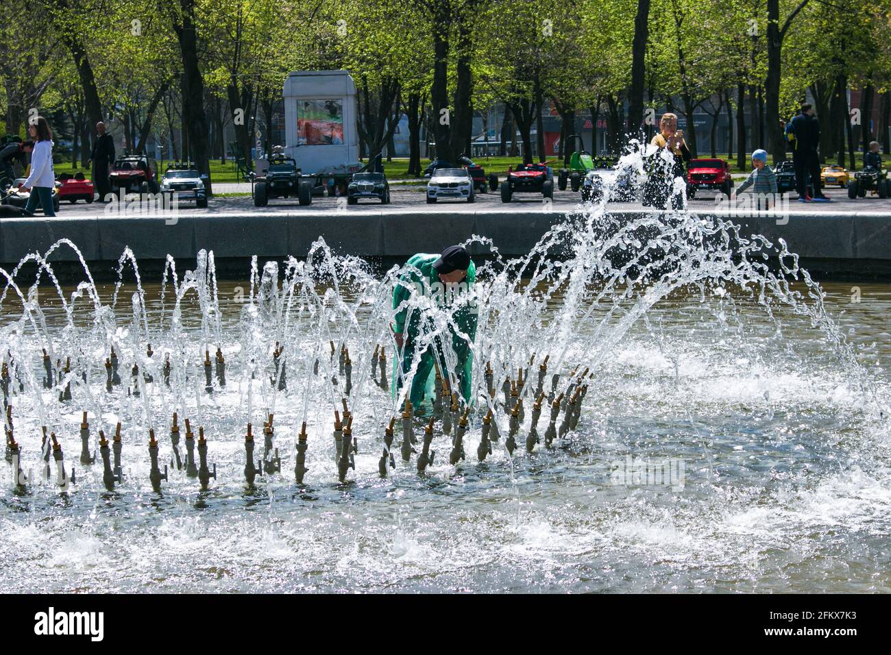 Dnepropetrovsk, Ucraina - 01.05.2021: I servizi municipali regolano le fontane prima del caldo estivo. Un operaio vestito ripara una fontana della città. Foto Stock