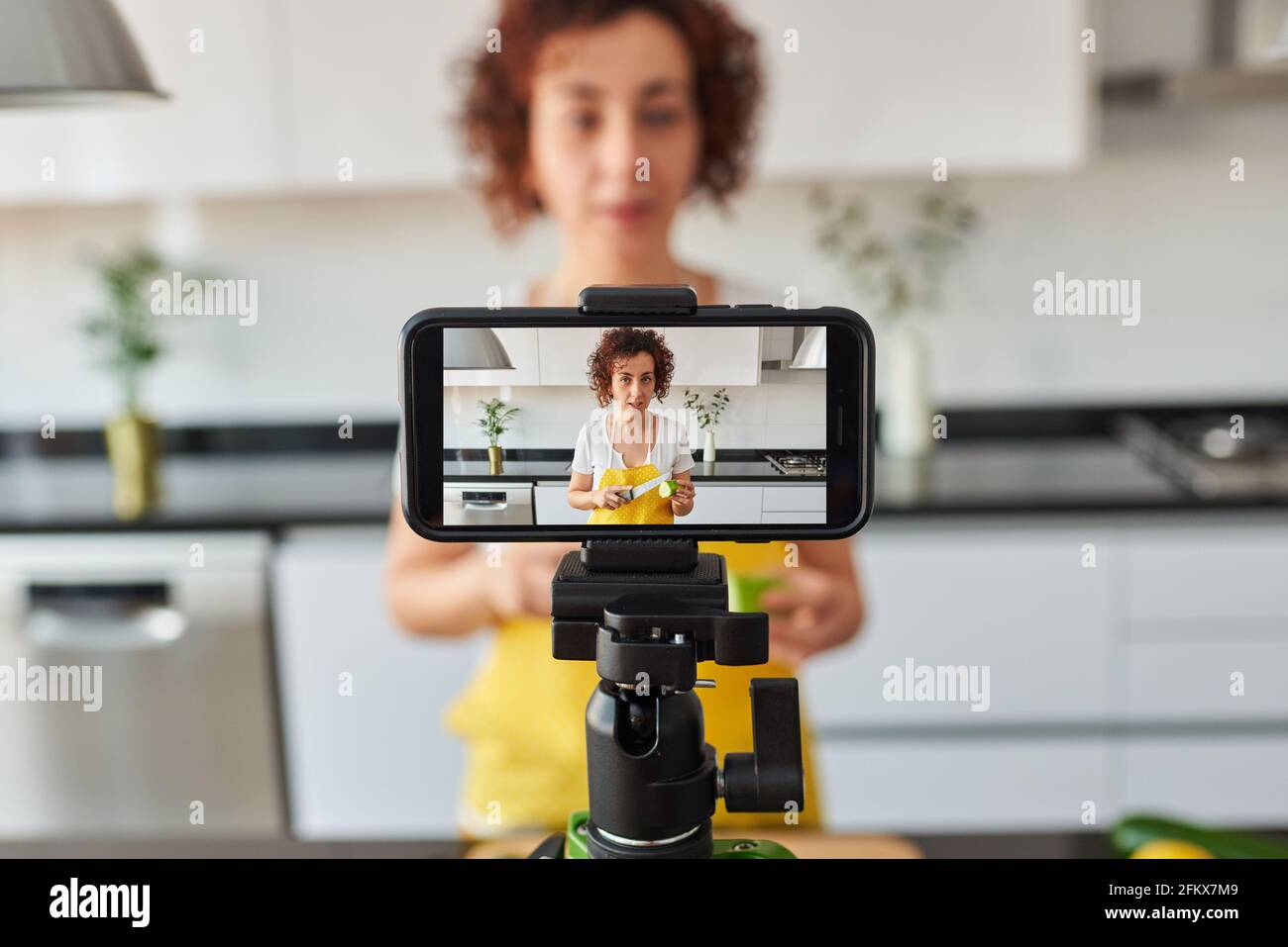 La donna youtuber si registra con il suo smartphone in cucina mentre si  prepara una ricetta di insalata, c'è luce naturale e lei indossa una a  gialla Foto stock - Alamy