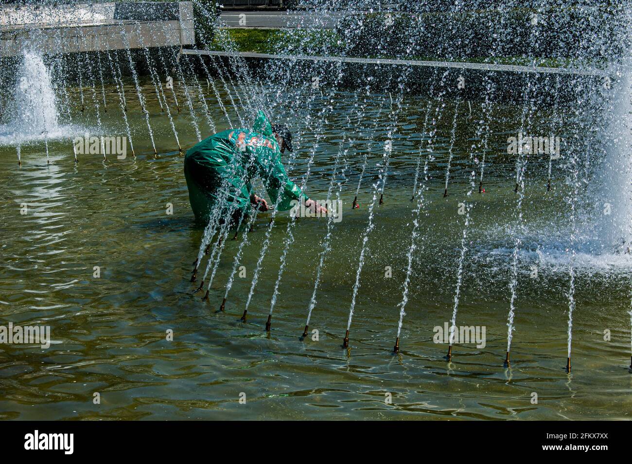 Dnepropetrovsk, Ucraina - 01.05.2021: I servizi municipali regolano le fontane prima del caldo estivo. Un operaio vestito ripara una fontana della città. Foto Stock