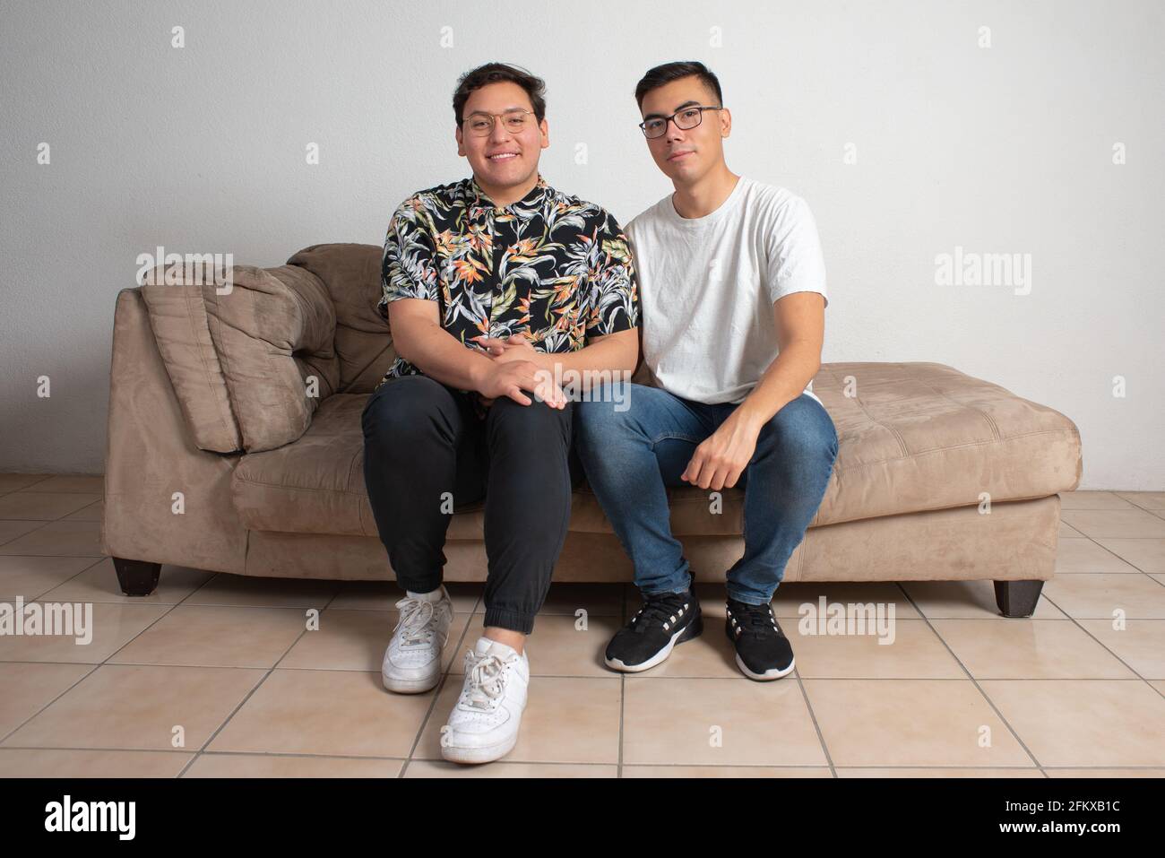 coppia maschile seduta nel loro soggiorno vuoto aspetto felice all'orizzonte Foto Stock