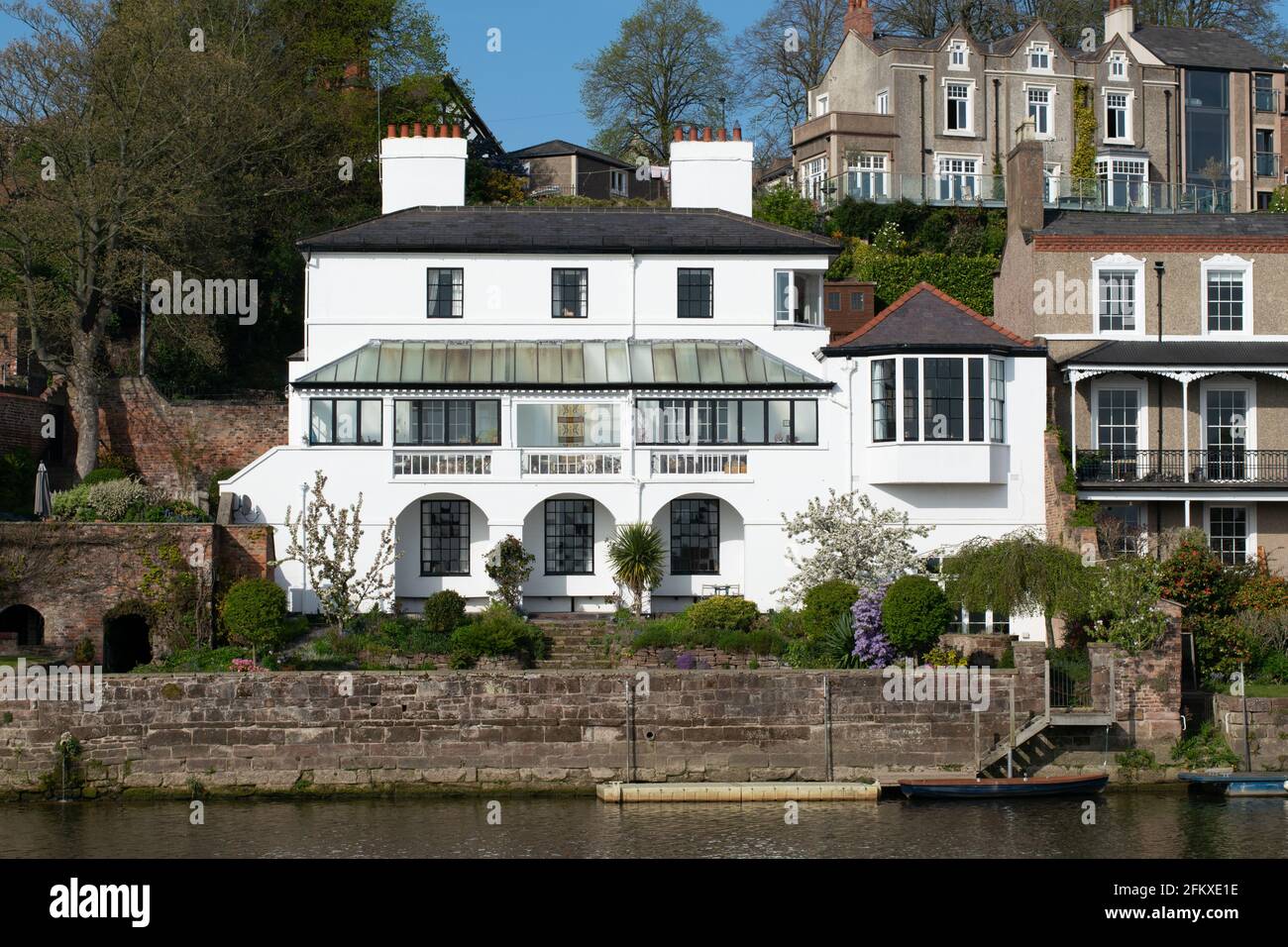 Proprietà dipinta di bianco sul lungomare con barca e giardino primaverile sul fiume Dee, la Mount Road. Chester, Cheshire, Regno Unito. Case britanniche Foto Stock