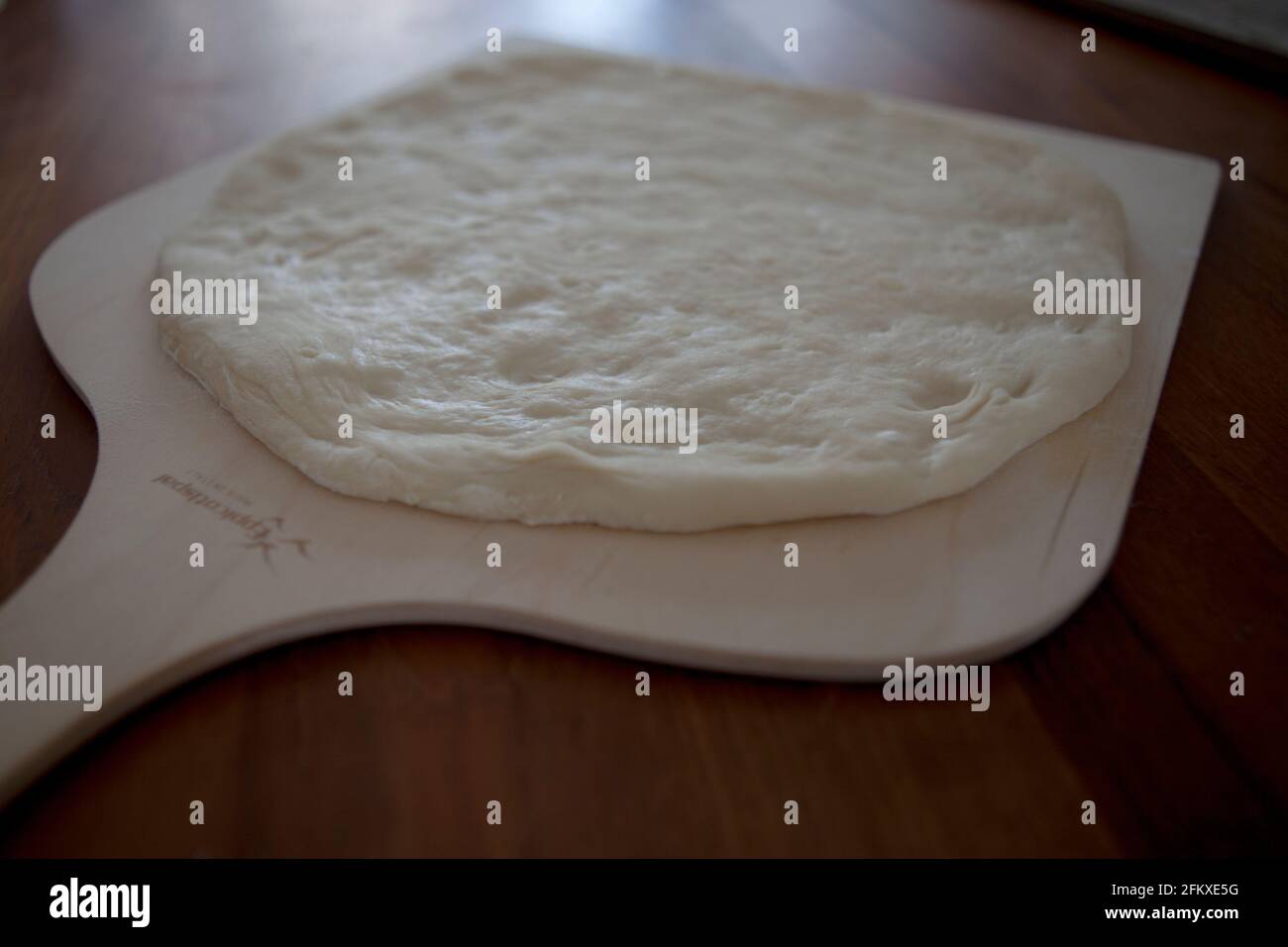 Pizza a base fatta in casa su una pagaia di legno Foto Stock