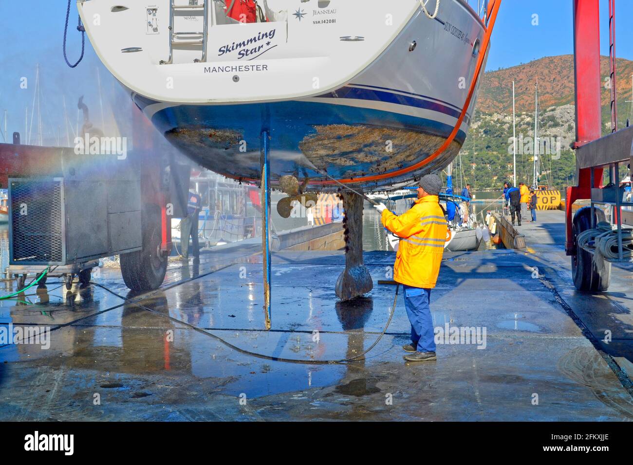 Yacht da crociera che viene sollevato e jet-lavata per rimuovere la incrostazione marina. Foto Stock