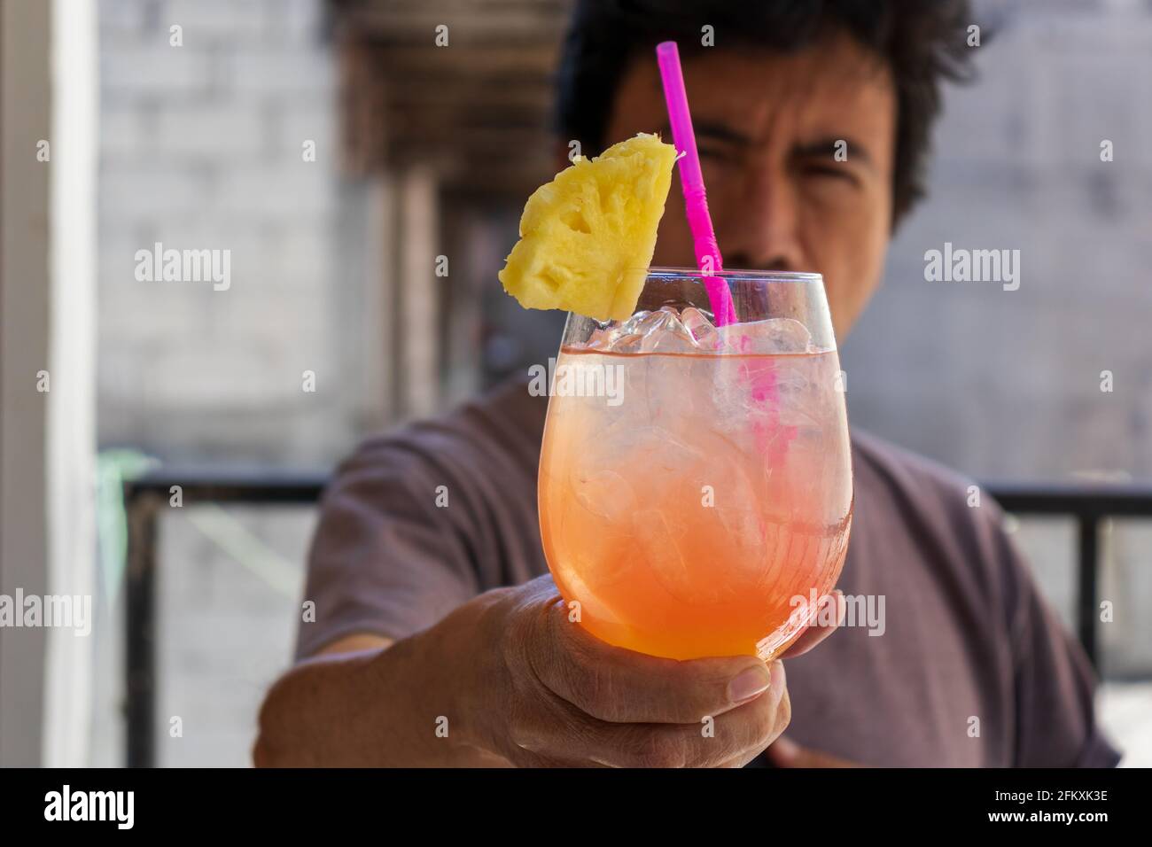 Uomo che tiene un cocktail tequila alba con fetta di ananas per concetto di bevanda di primavera ed estate Foto Stock