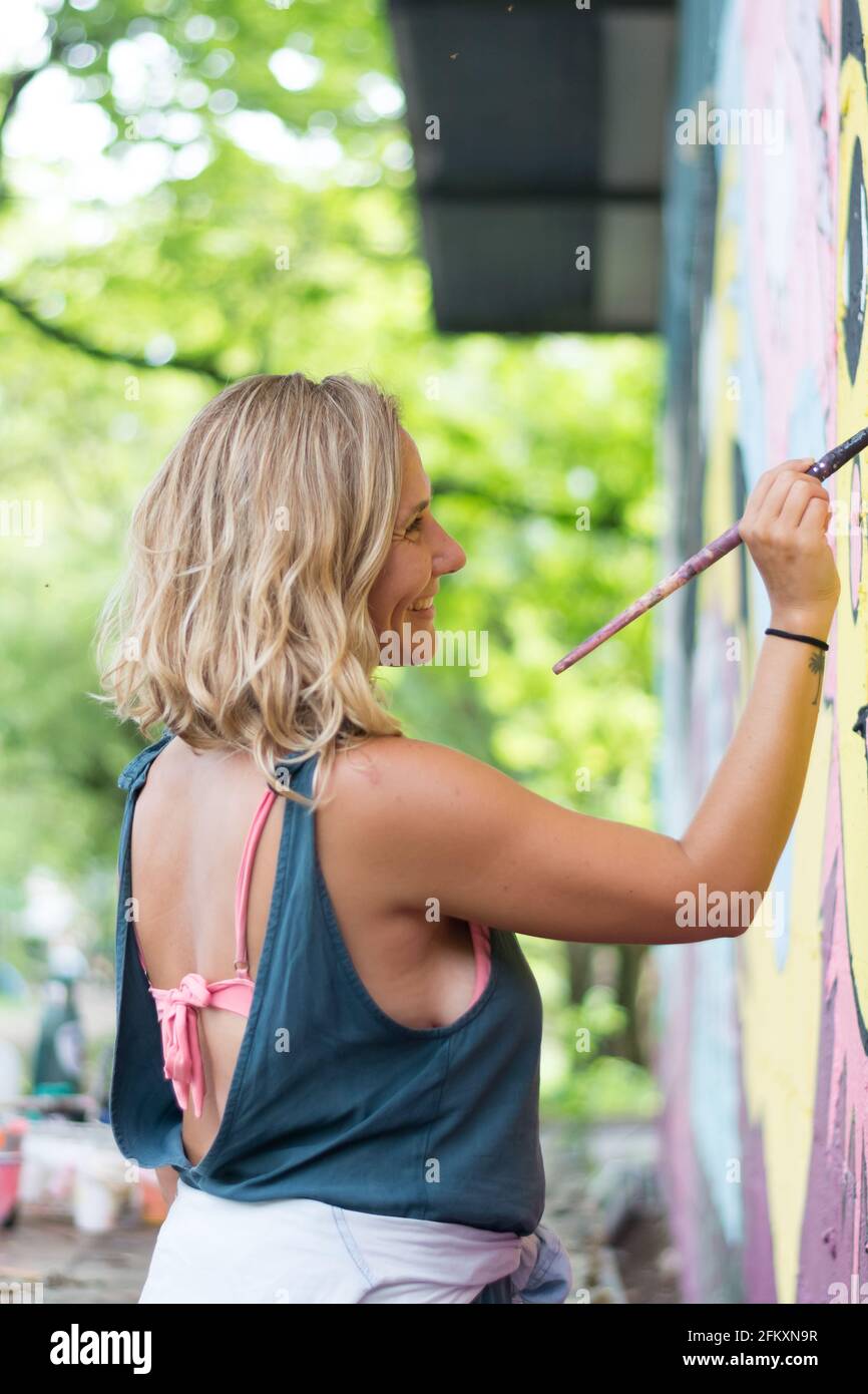 Vista laterale di artista femminile parete verniciatura Foto Stock
