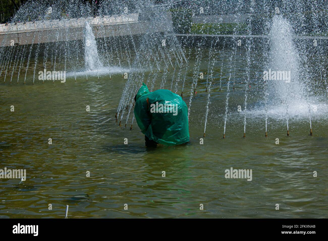 Dnepropetrovsk, Ucraina - 01.05.2021: I servizi municipali regolano le fontane prima del caldo estivo. Un operaio vestito ripara una fontana della città. Foto Stock
