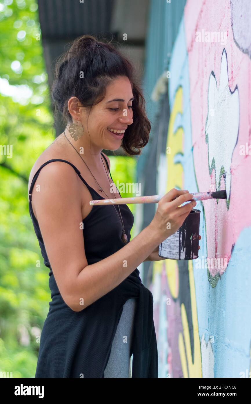 Sorridente artista femminile pittura murale sulla parete Foto Stock