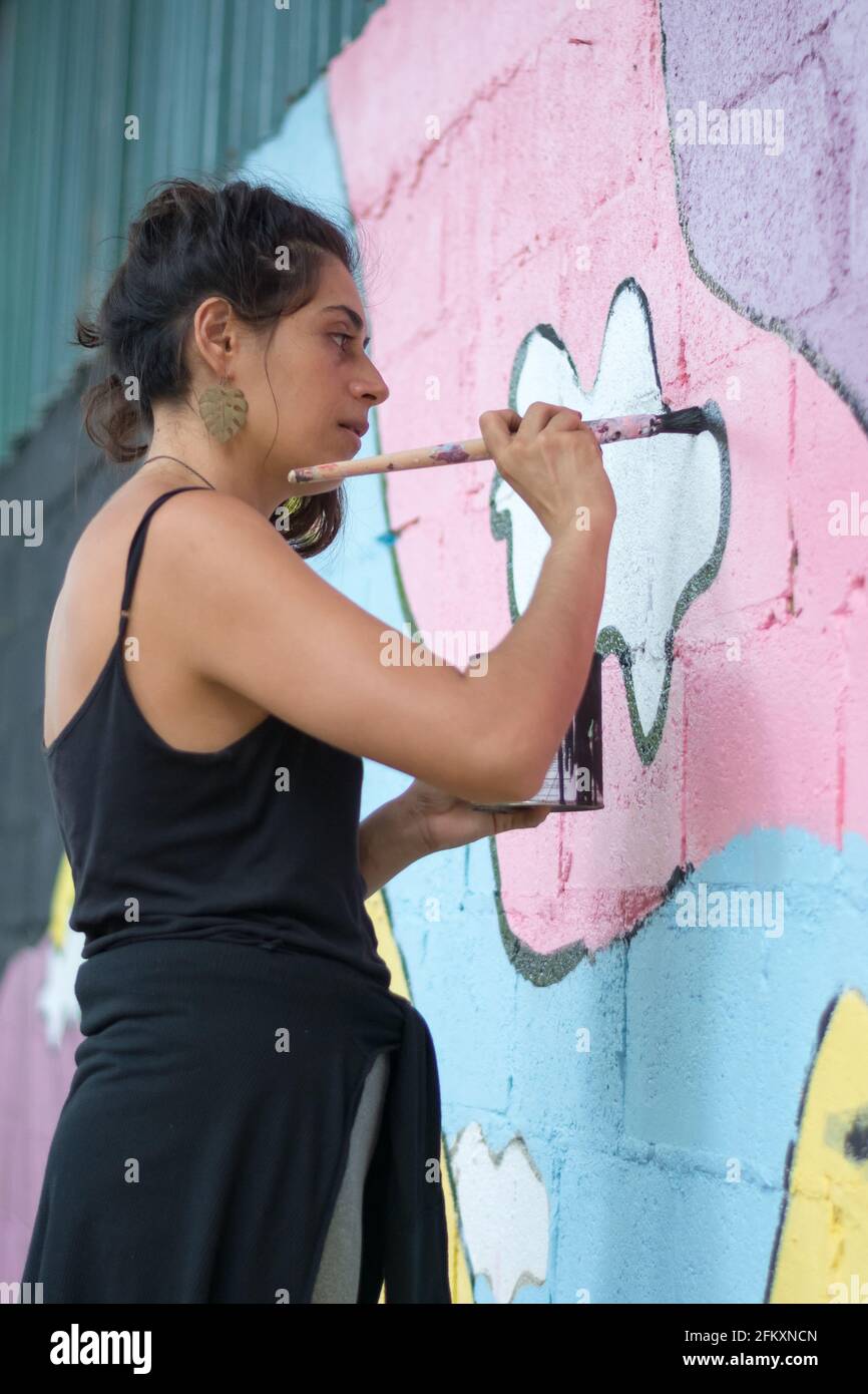Concentrato artista femminile pittura murale sulla parete Foto Stock