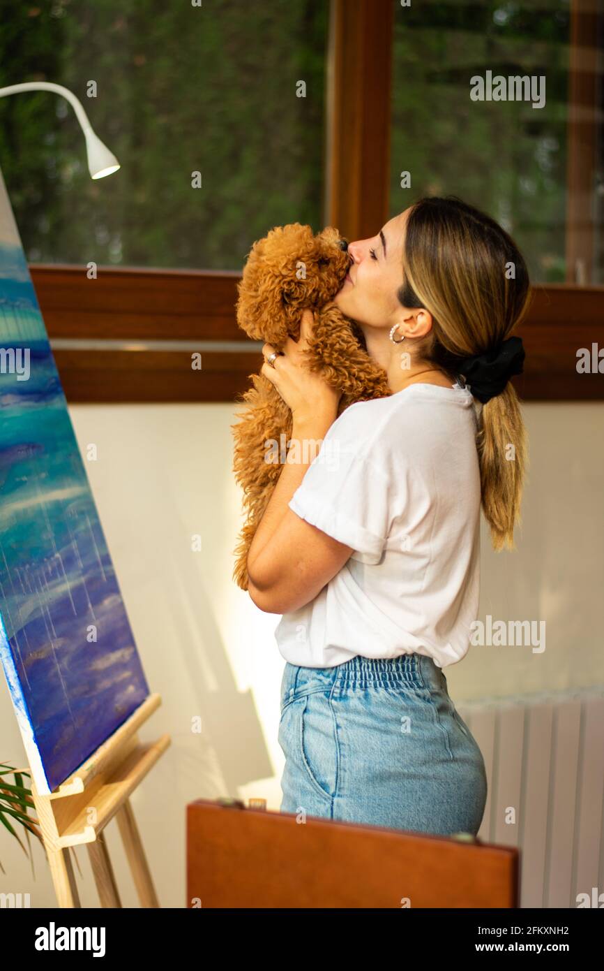 giovane bionda che bacia il suo animale domestico in classe di pittura Foto Stock