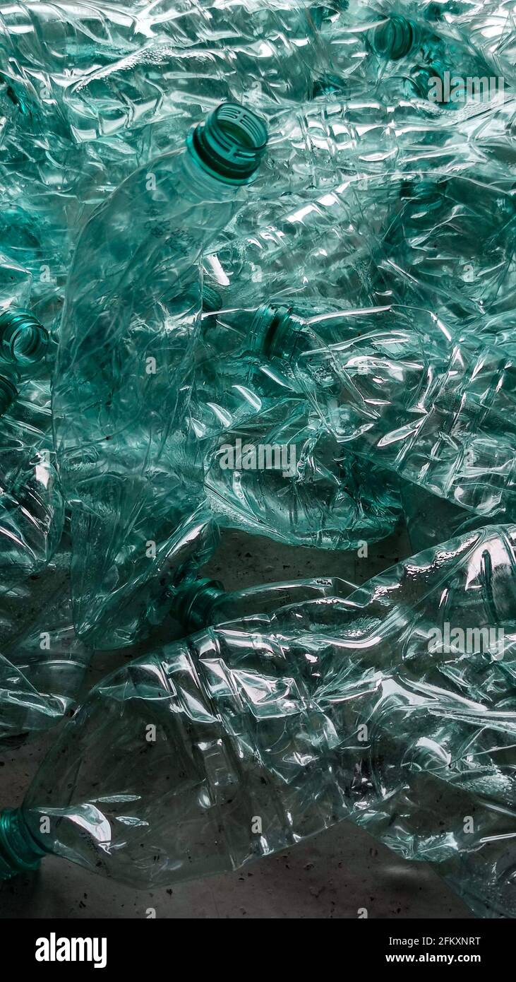 Pila di bottiglie di plastica schiacciate che si stagliano sul pavimento imbottigliare Foto Stock
