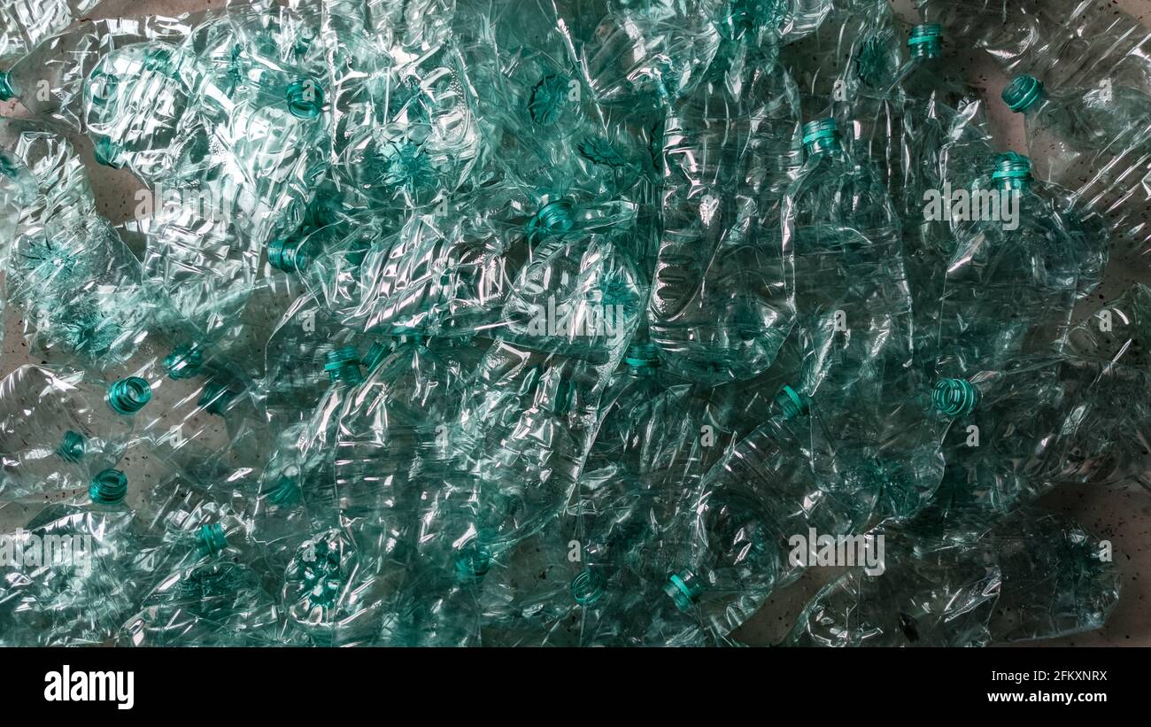 Pila di bottiglie di plastica schiacciate che si stagliano sul pavimento disposizione piatta Foto Stock