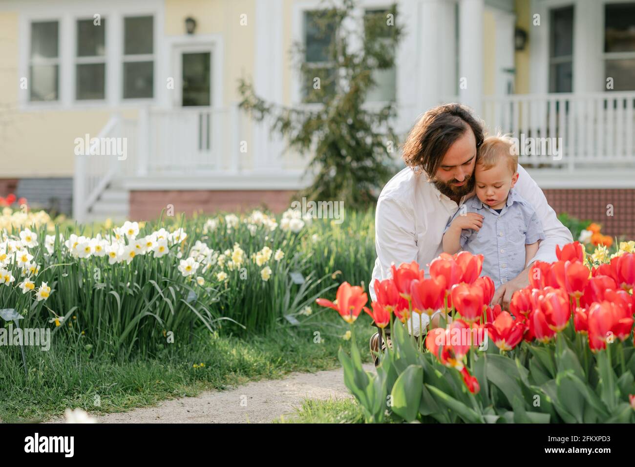 Padre insegnando al figlio del toddler circa i fiori nel giardino del tulipano Foto Stock