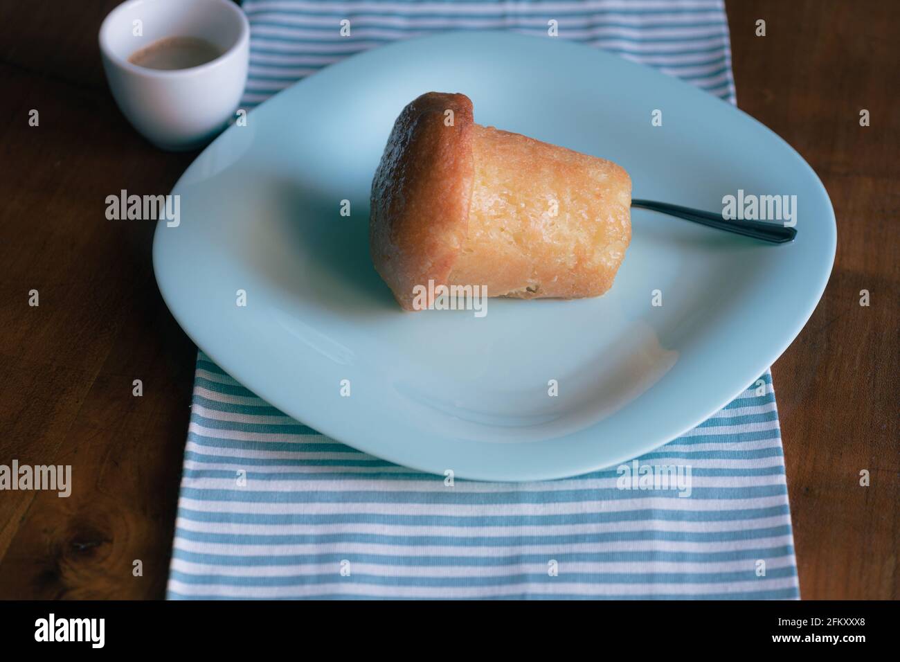Famosa baba napoletana e caffè espresso su un piatto blu per uno spuntino dolce Foto Stock