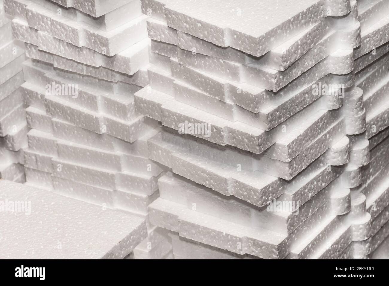 Una pila di materiale espanso industriale in polistirene bianco immagazzinato in magazzino. Foto Stock