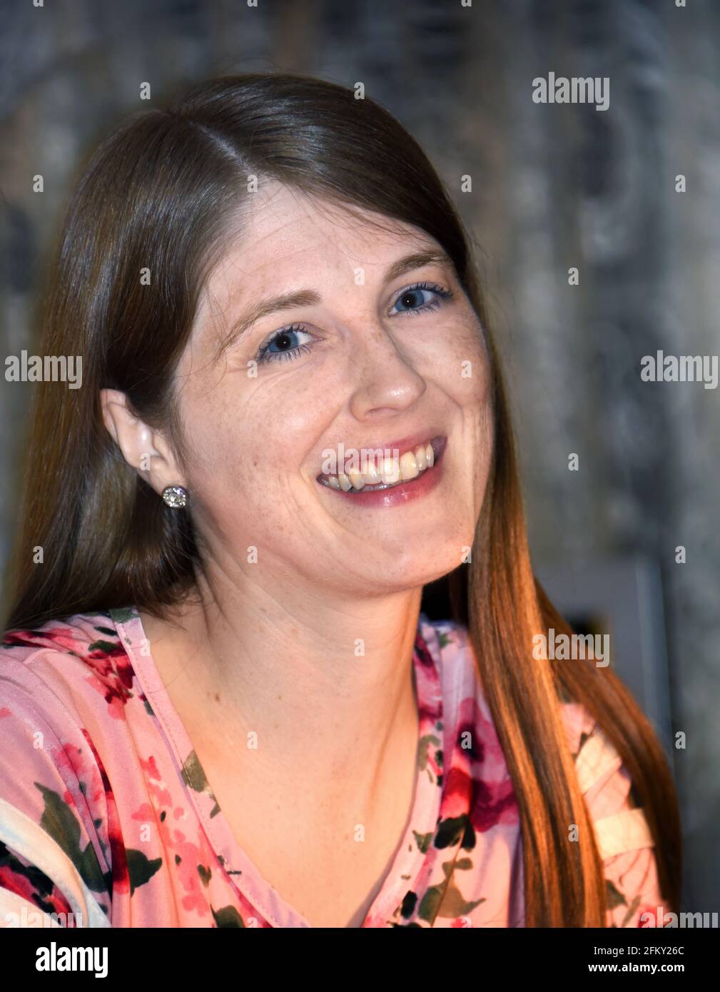 Il sorriso luminoso illumina il volto di questa giovane donna. Ha belle freckles spruzzato attraverso la sua faccia. Primo piano. Foto Stock