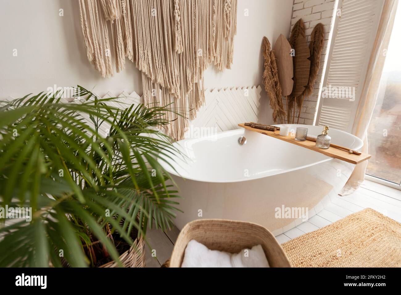 Accogliente interno bagno con grande vasca, piante e decorazioni rustiche Foto Stock