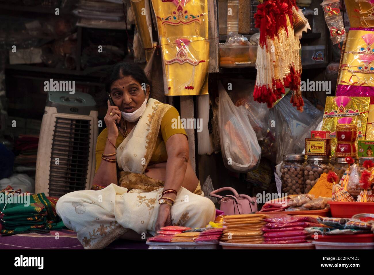 Donna in stallo che vende spezie indiane che parlano al telefono. Discutendo, Mandai, Pune, Maharashtra, India Foto Stock