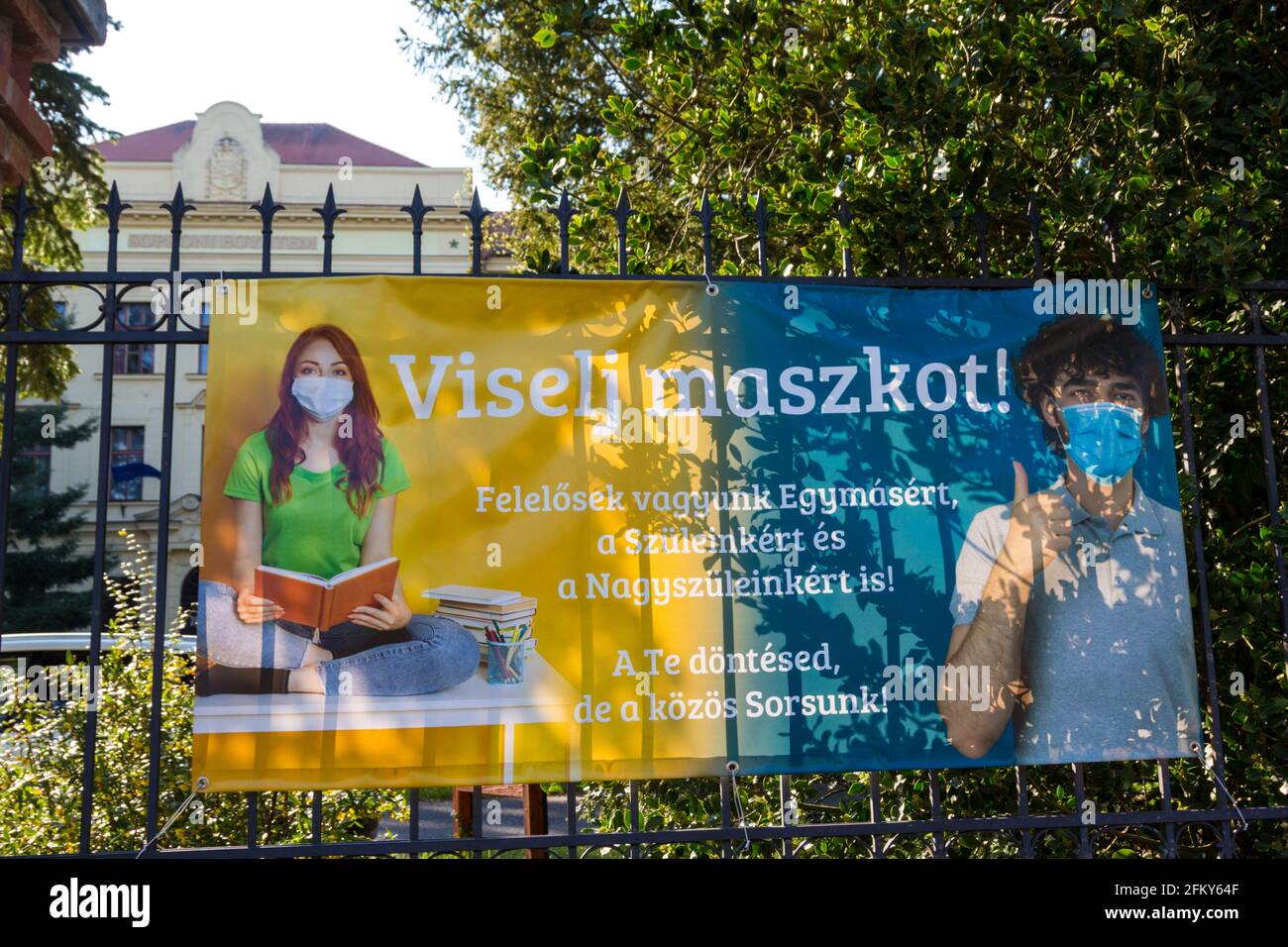 Banner 'Viselj maszkot' (indossare una maschera facciale) fissato sulla recinzione della Sopron University durante la pandemia COVID19, Sopron, Ungheria Foto Stock