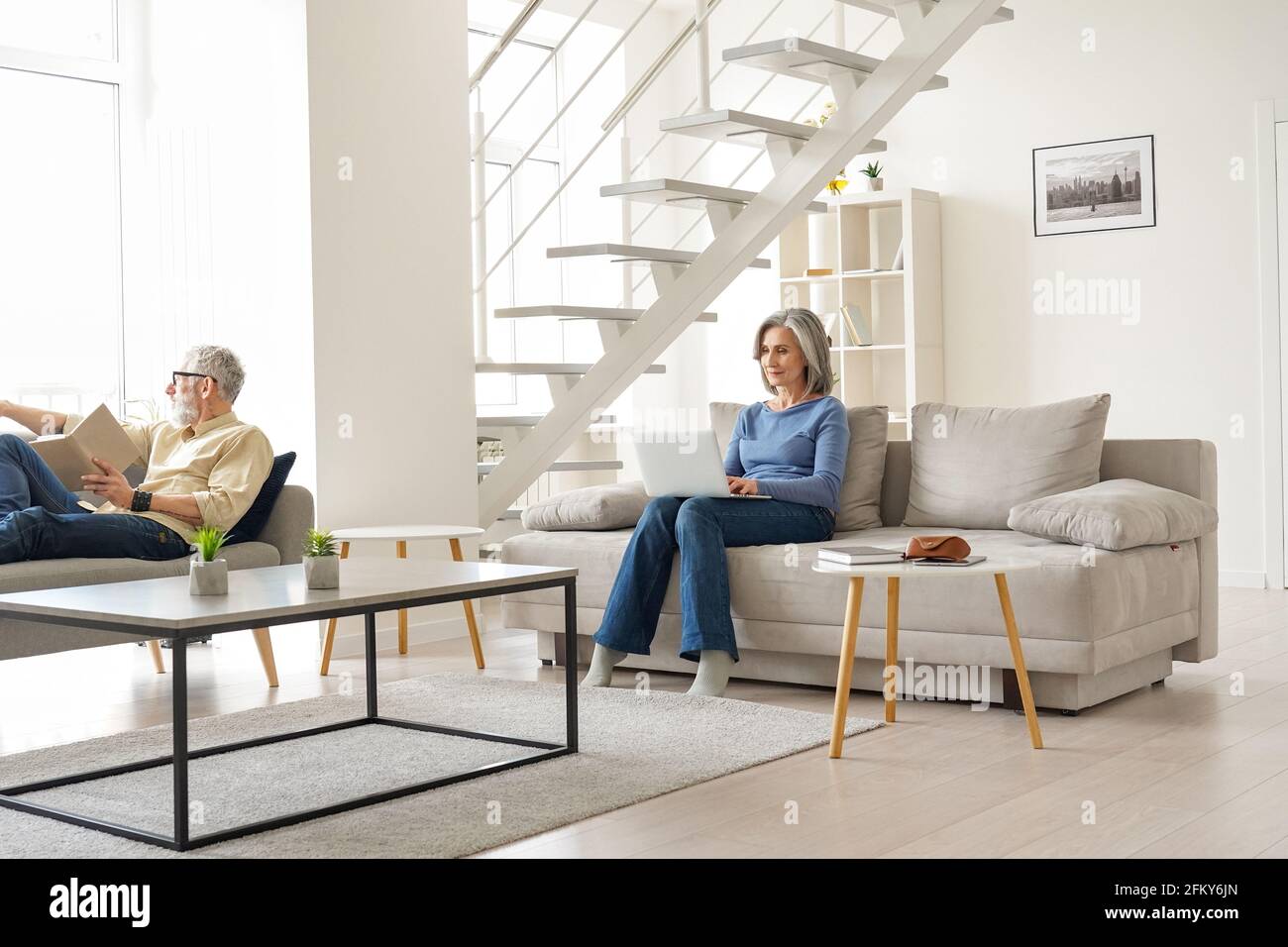 Una coppia anziana di famiglia trascorre del tempo a casa in un moderno soggiorno. Foto Stock