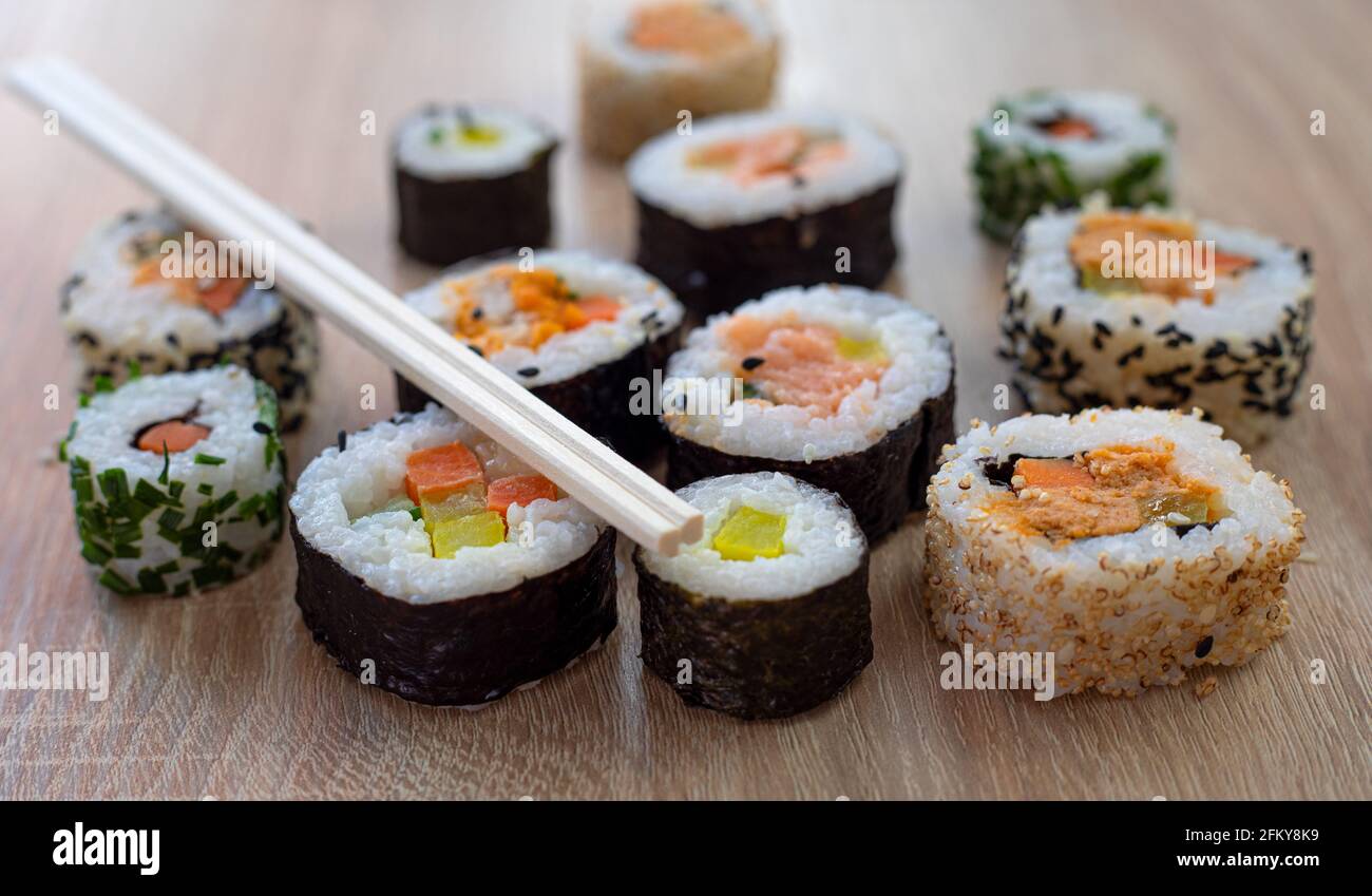 Set di sushi di maki con bastoncini di chopsticks su sfondo di legno per menu Foto Stock