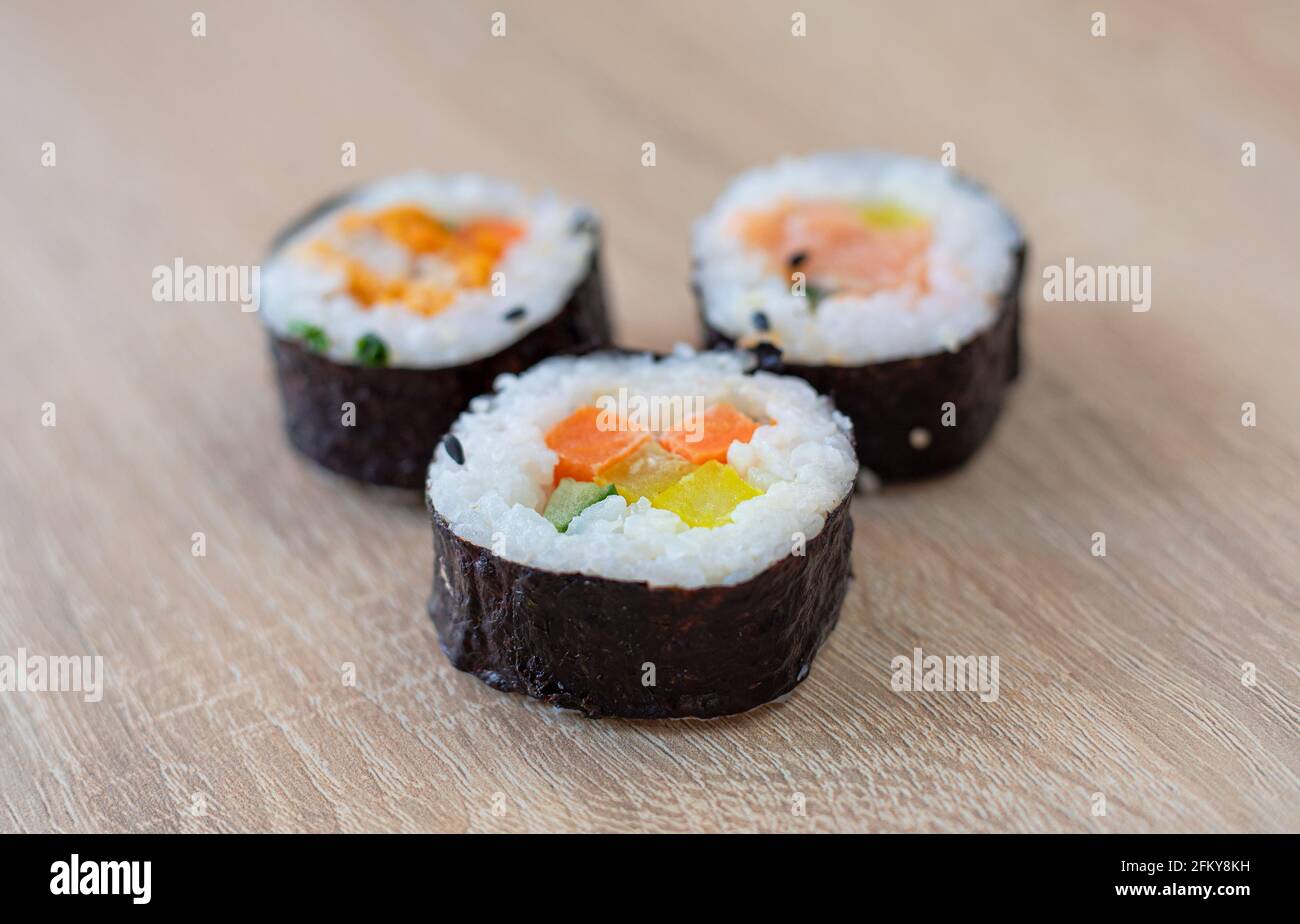 Tre panini di sushi su sfondo di legno Foto Stock