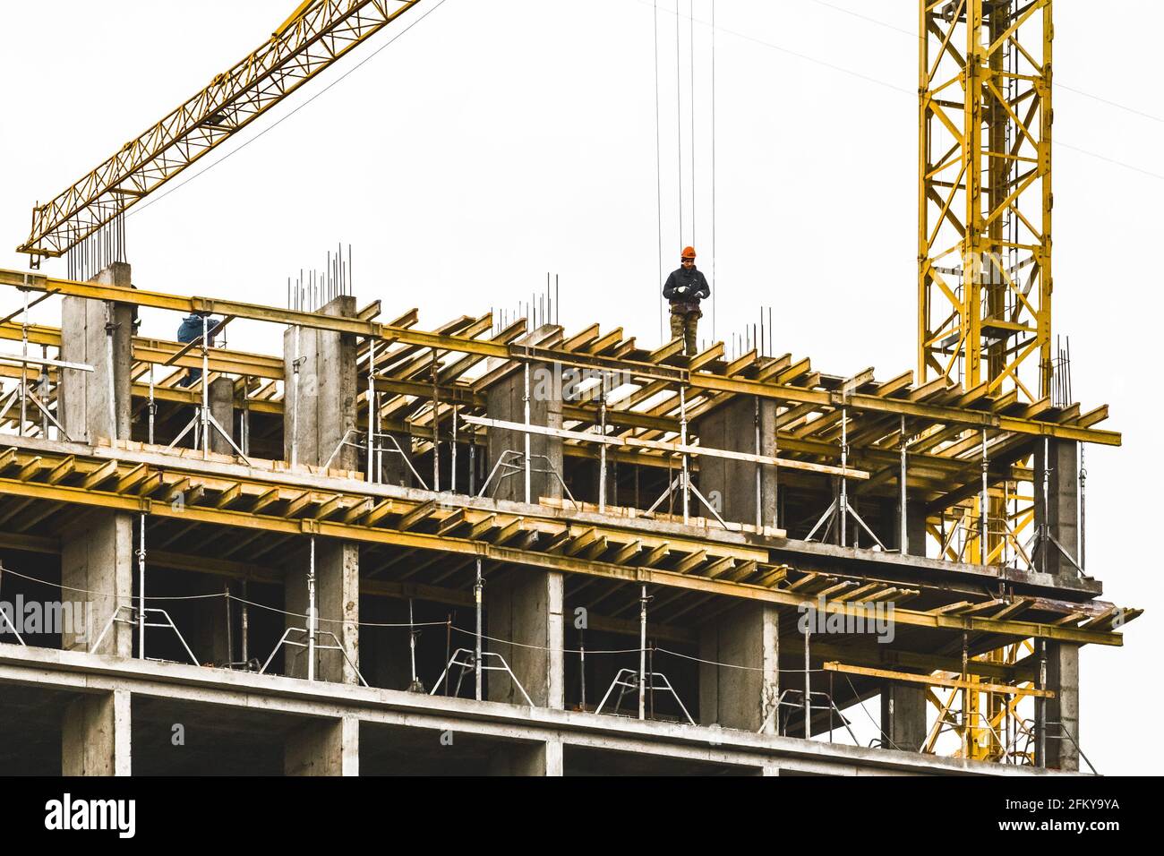 Bielorussia, Minsk - 06 marzo 2020: Un costruttore si trova sul bordo di un edificio in costruzione, una professione pericolosa. Foto Stock