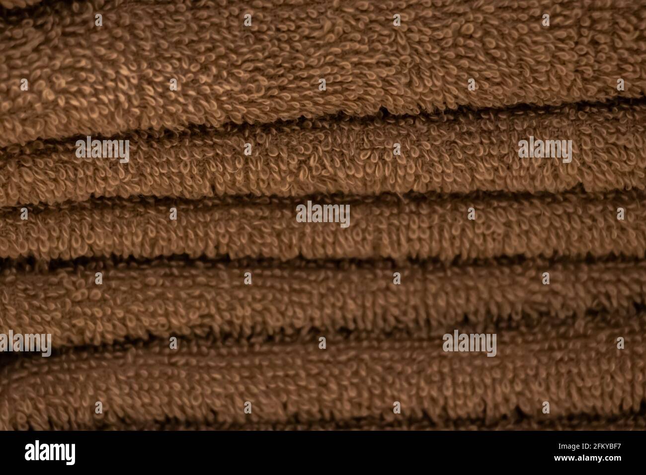 Una pila di accessori da bagno morbidi. Texture di spugna marrone primo piano asciugamano. Foto Stock