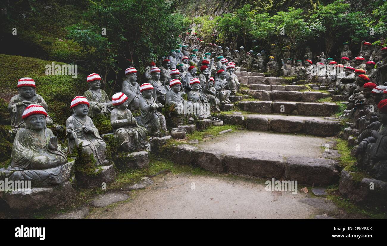 Statue di Buddha con offerte di cappelli a maglia lungo il sentiero del santuario che rappresenta I primi 500 discepoli dello storico Buddha Shakyamuni a. Il tempio diam Foto Stock