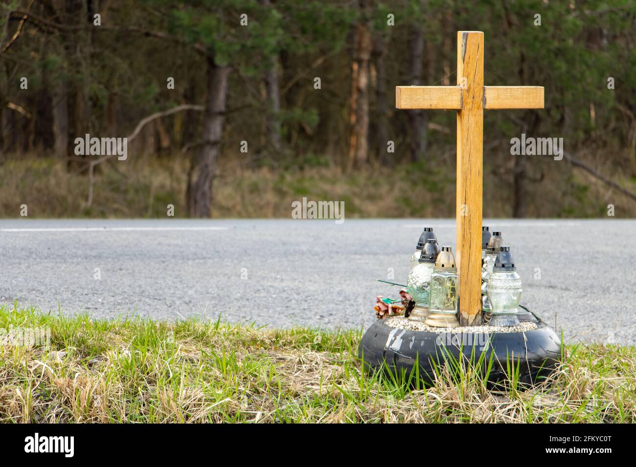 Una croce commemorativa a lato della strada con candele che commemorano la tragica morte accanto a una strada. Foto Stock