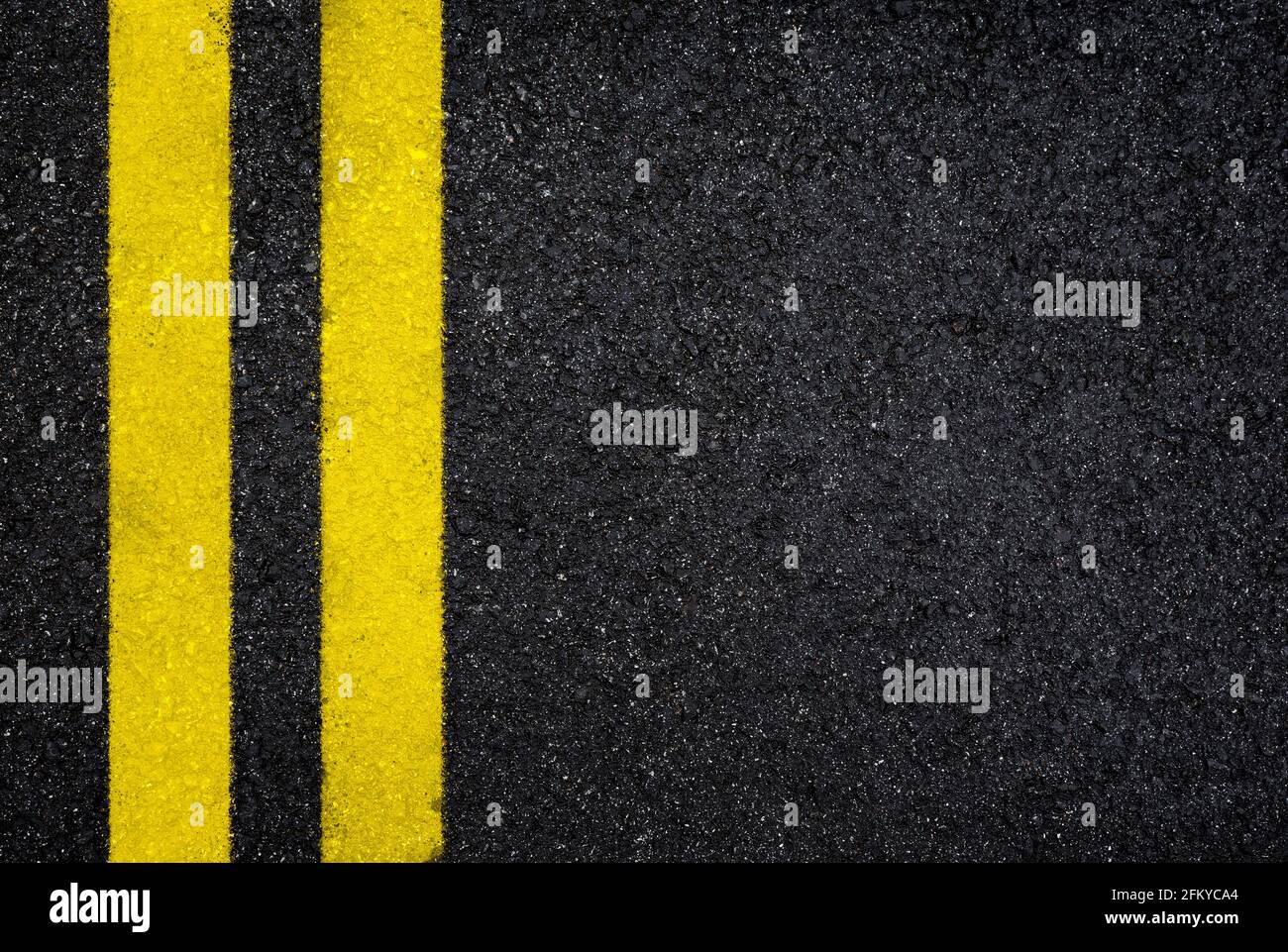 Vista dall'alto della strada asfaltata umida scura con doppia linea gialla. Sfondo testurizzato full frame ad alta risoluzione in asfalto nero, vista dall'alto. Foto Stock