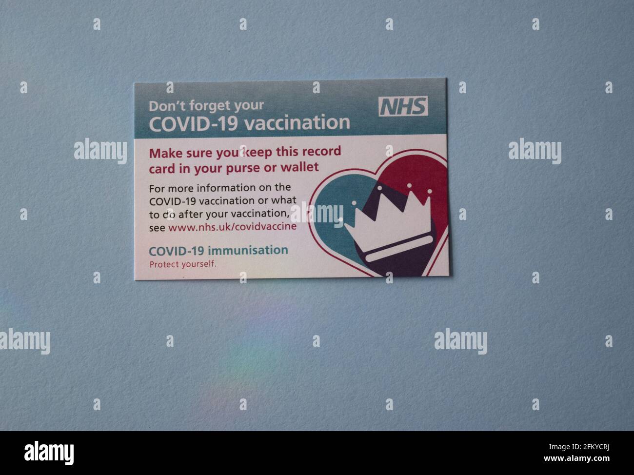Scheda di vaccinazione NHS Covid-19 su sfondo blu. Foto Stock