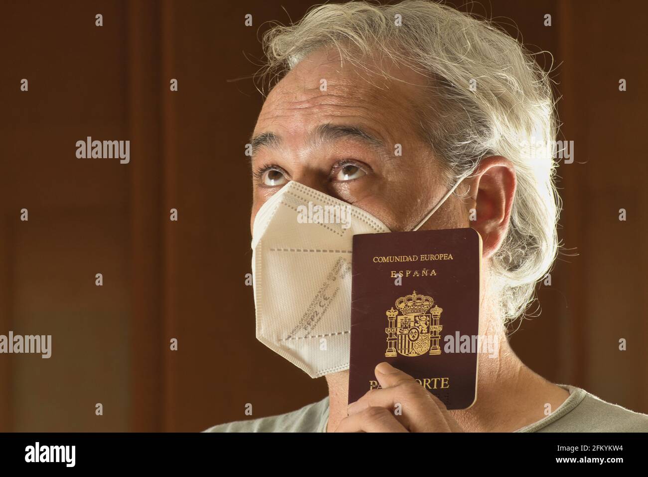 uomo maturo con maschera pensando con un passaporto in mano Foto Stock