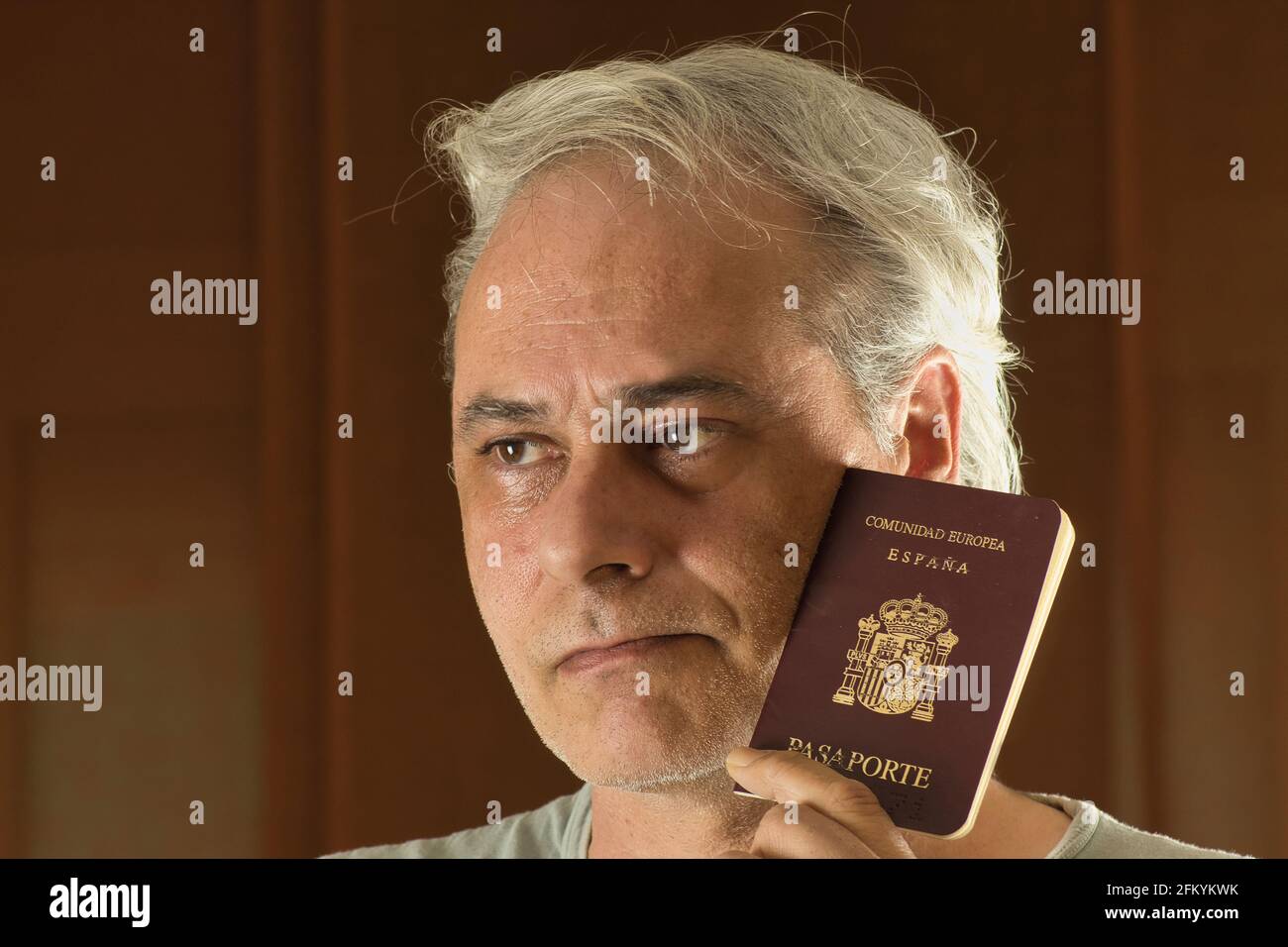uomo maturo che pensa con un passaporto in mano Foto Stock