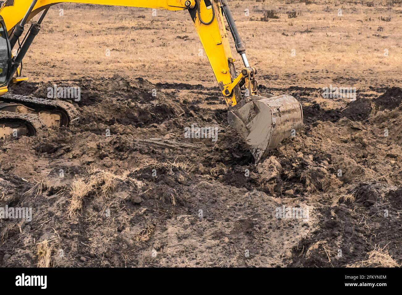 Il lavoratore di costruzione su un'attrezzatura di escavatore cingolato scava una trincea in un'area industriale. Lavori di scavo con terra e suolo. Foto Stock