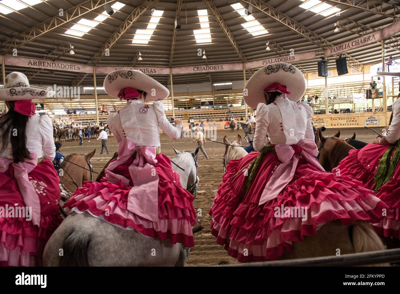 Gli Escaramuzas mettono in mostra le loro notevoli abilità di guida in sella e l'abbigliamento tradizionale al Campeonato Millonario Lienzo de Charro di Jalisco, Messico Foto Stock