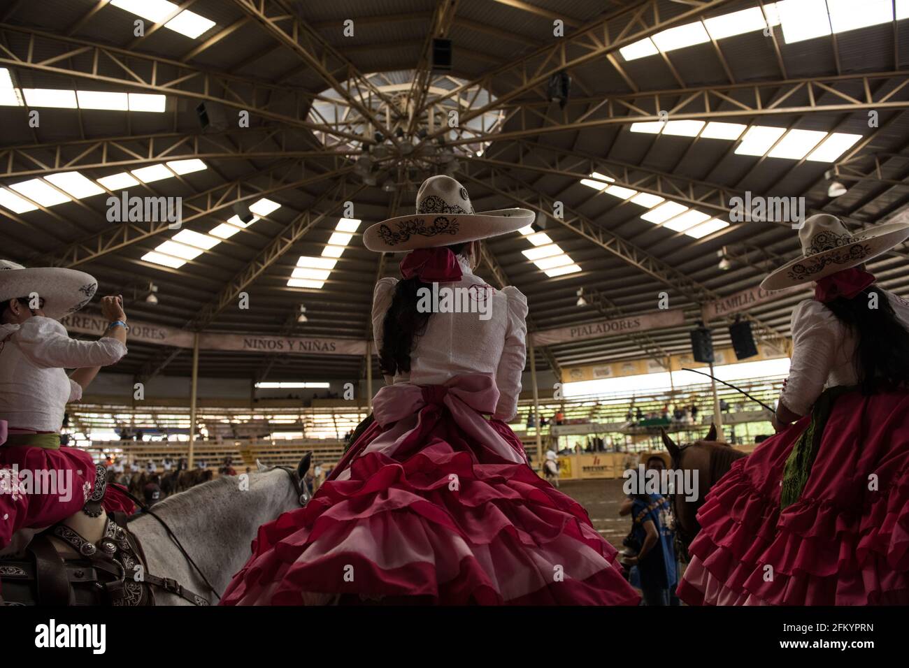 Gli Escaramuzas mettono in mostra le loro notevoli abilità di guida in sella e l'abbigliamento tradizionale al Campeonato Millonario Lienzo de Charro di Jalisco, Messico Foto Stock