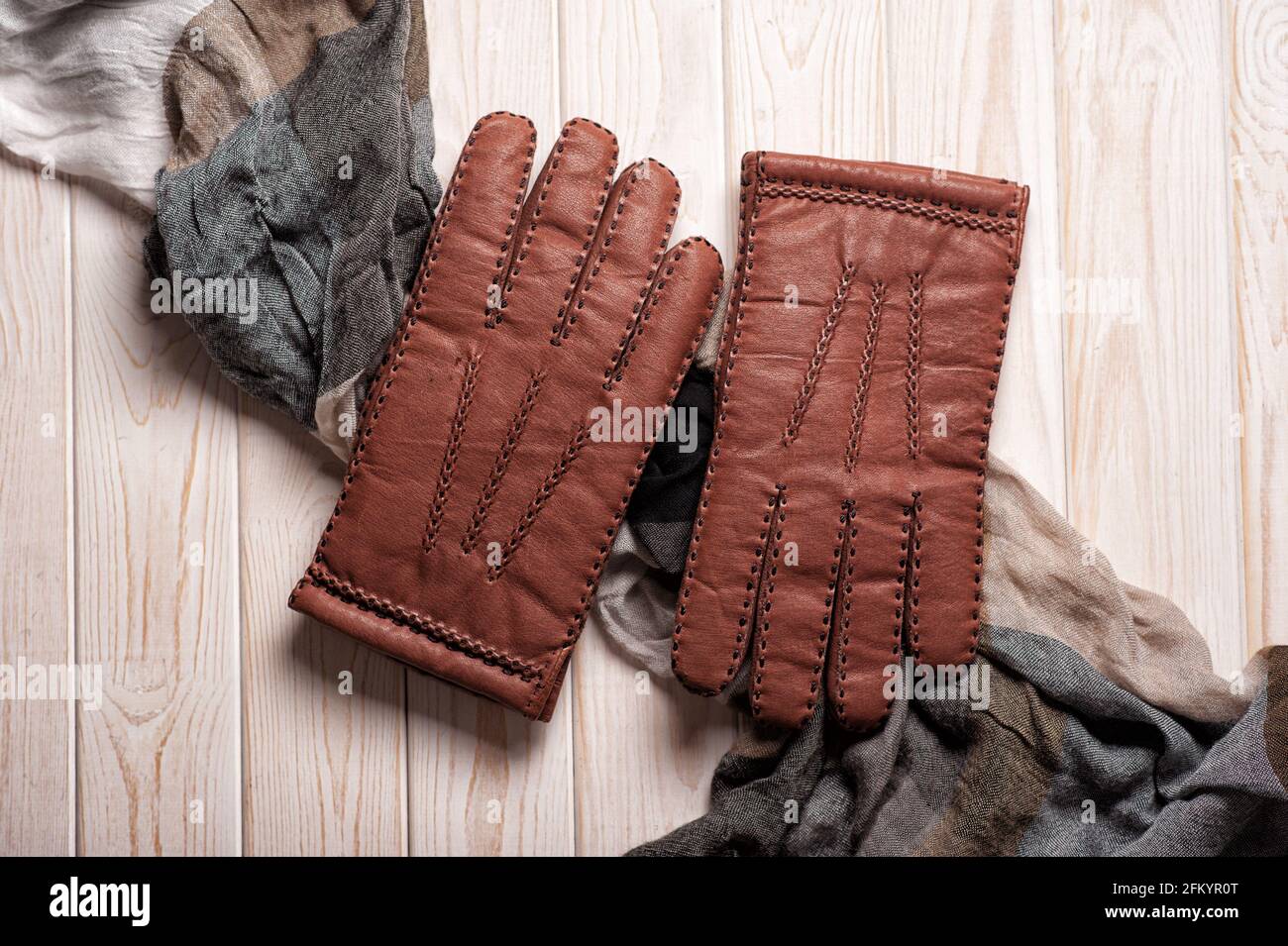 Coppia di guanti in pelle marrone da uomo e altri accessori da uomo su  sfondo in legno Foto stock - Alamy