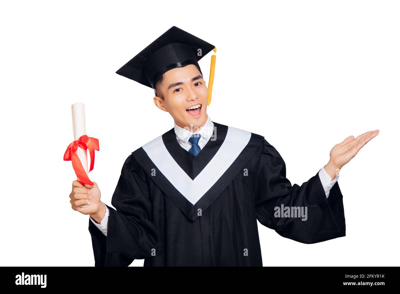 giovane uomo in abito di graduazione nero e cappello che tiene un diploma isolato su sfondo bianco Foto Stock