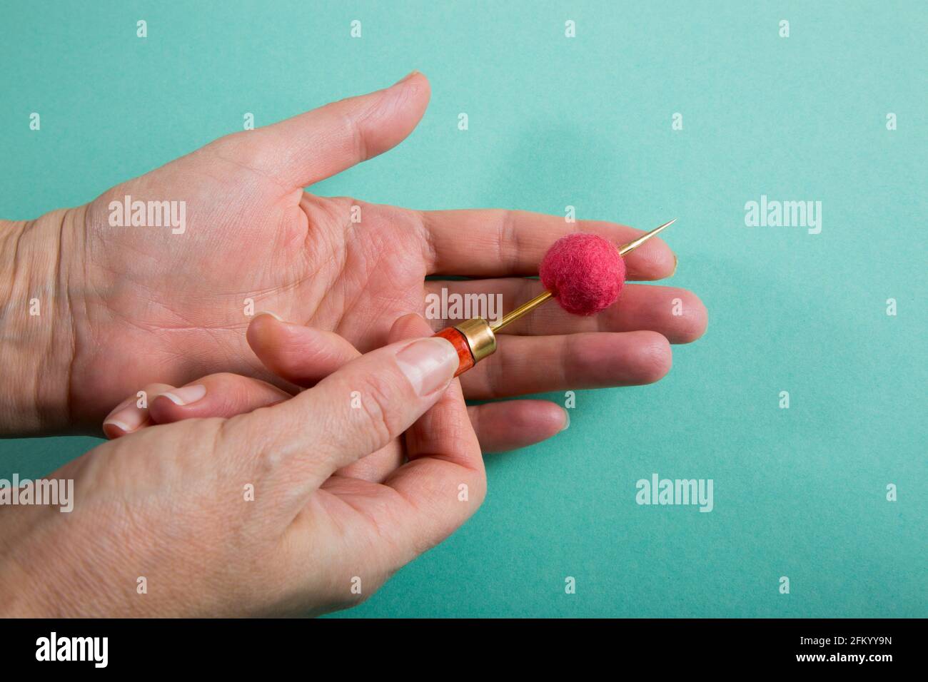 Una donna pierces una palla di lana con un awl mentre si fa un prodotto Foto Stock