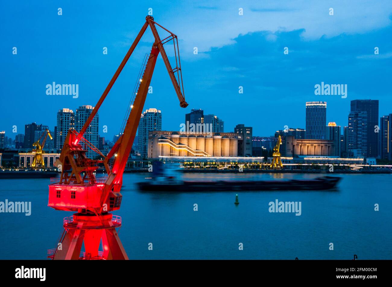 Una vecchia gru di trasporto nel distretto di Yanpu incornicia una barca di carico e gli edifici sul lato di Pudong del fiume Huangpu, Shanghai, Cina. Foto Stock