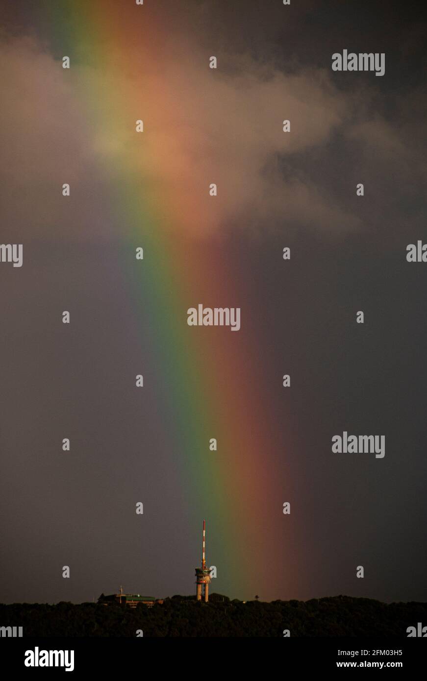Arcobaleno luminoso che scende dietro il faro sul bluff Foto Stock